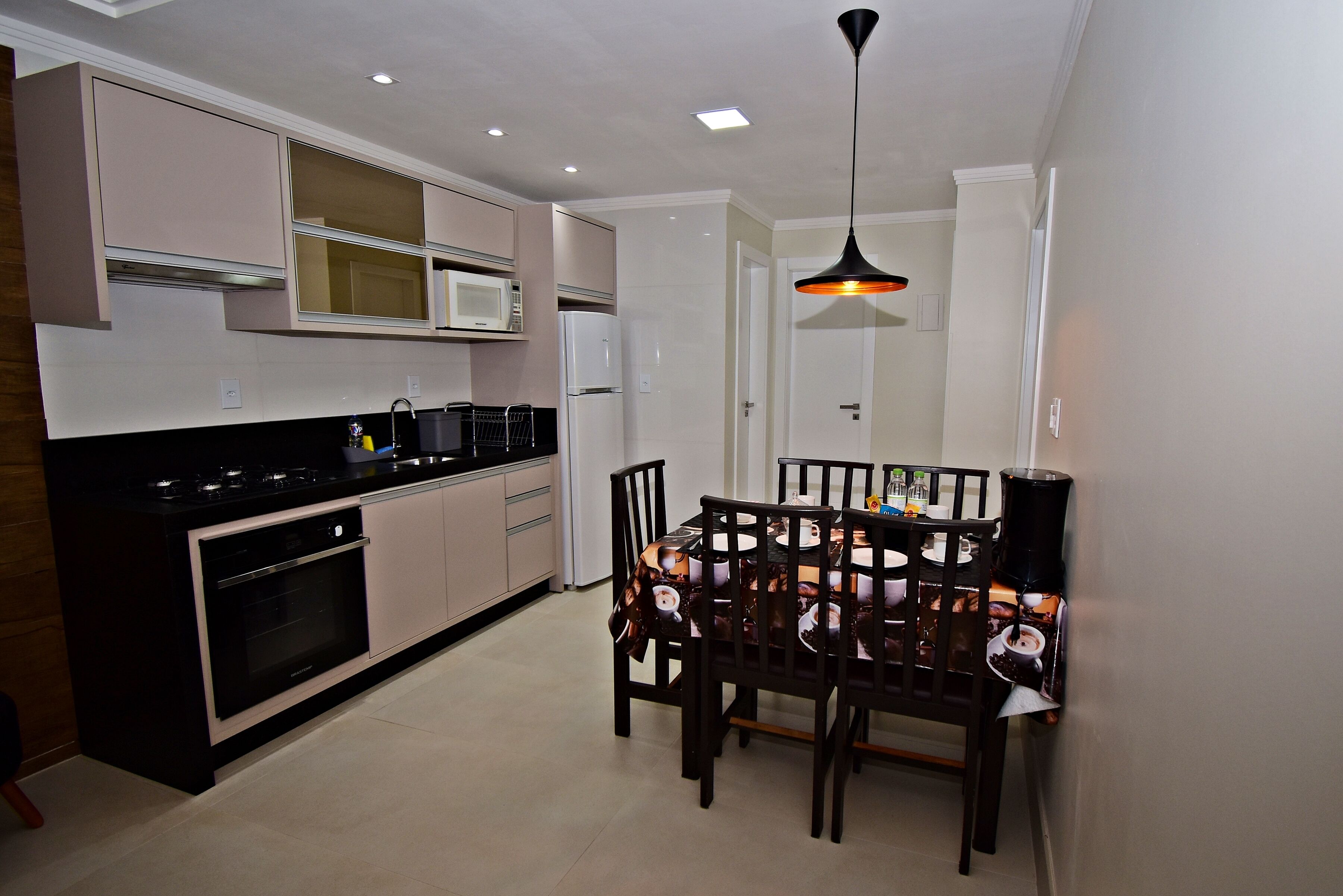 A modern kitchen with a dining area, featuring a built-in microwave, oven, and a dining table with chairs.