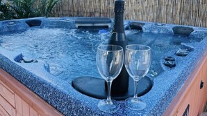 A hot tub with two empty wine glasses and a bottle of champagne. - Key Largo home with new hot tub! (Key Largo)