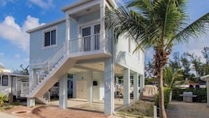 A two-story house with a balcony, a covered porch, and a palm tree in the background. - Key Largo home with new hot tub! (Key Largo)