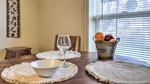 Una mesa para comer con individuales, una copa de vino, un bol y una cesta de frutas.