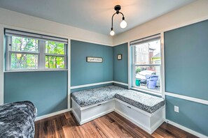 A corner room with a built-in bench, large windows, and a ceiling light fixture.