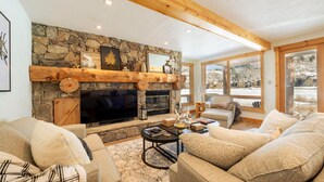 A cozy living room with a stone fireplace, a flat-screen TV, and comfortable seating.