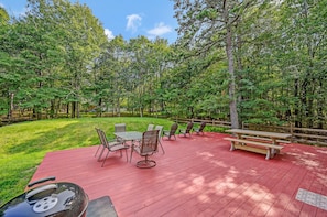 Eine rote Terrasse mit Picknicktischen und -stühlen, umgeben von einem Wald.