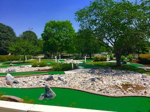 A miniature golf course with multiple holes, green artificial turf, and scattered rocks.