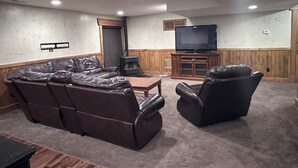 Un salon chaleureux avec un canapé en cuir, un fauteuil inclinable et un téléviseur posé sur un meuble en bois.