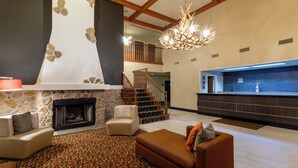 A spacious living area with a fireplace, a staircase, and a kitchen area. - GrandStay Hotel & Suites - Waunakee  (Waunakee)