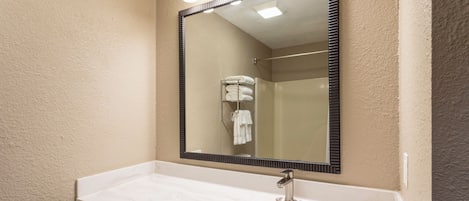 A bathroom with a white sink, a large mirror, and a towel rack.