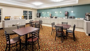 A hotel room with a dining area, kitchenette, and a patterned carpet. - GrandStay Hotel & Suites - Waunakee  (Waunakee)