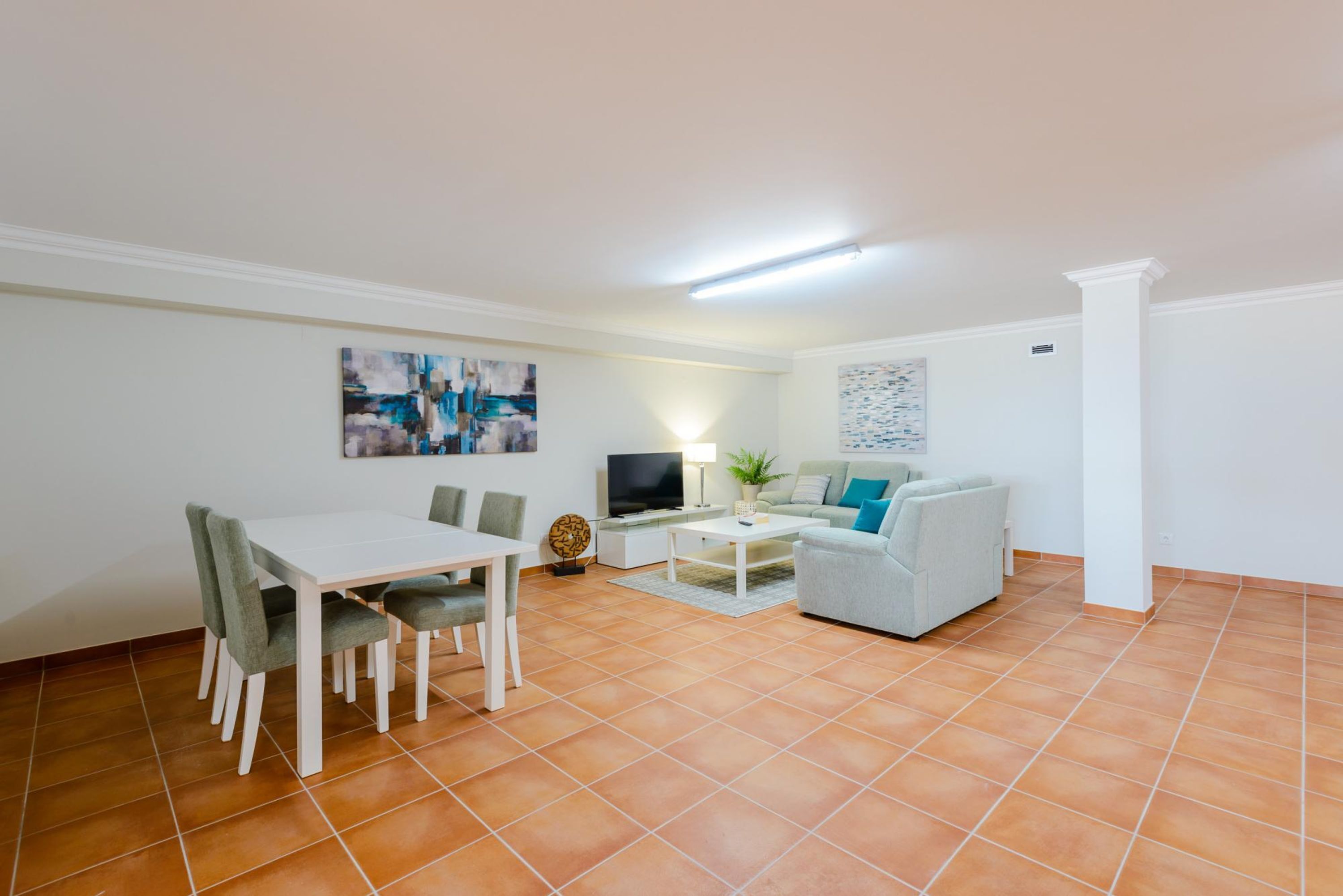 A modern living room with a dining table, sofa, and TV.