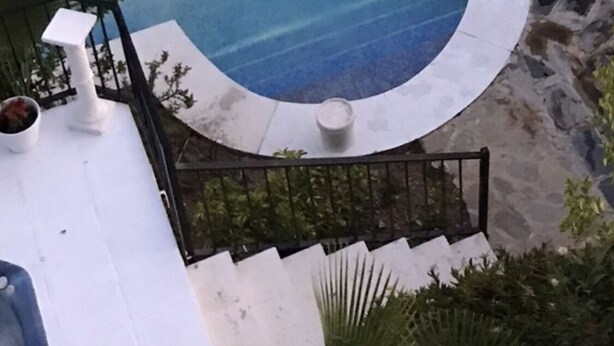 A swimming pool with a person in the water, surrounded by lounge chairs and a small deck area. - Coast View Villa (Marbella)