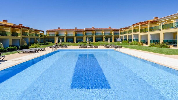 A hotel with a large swimming pool, multiple balconies, and outdoor seating areas. - Casa Mapie - Boavista Golf Resort Spa (Lagos)