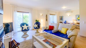 A living room with a sofa, armchairs, a coffee table, and a TV. - Casa Mapie - Boavista Golf Resort Spa (Lagos)