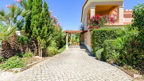 A paved pathway leading to a building with a tiled roof and a balcony with pink flowers. - Casa Mapie - Boavista Golf Resort Spa (Lagos)