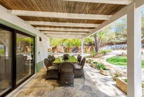 An outdoor patio with a dining table and chairs, surrounded by stone flooring and a pergola overhead. - Casa dos Sonhos in Vale do Lobo (Loulé)