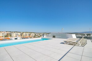 A rooftop pool area with a clear view of the cityscape in the background.