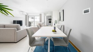 A modern living room with a grey sofa, a white dining table with two grey chairs, and a blue rug. - Lagos Town Centre Apartment (Lagos)