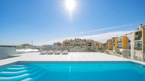 A rooftop swimming pool with lounge chairs, surrounded by buildings with balconies and a clear sky. - Lagos Town Centre Apartment (Lagos)