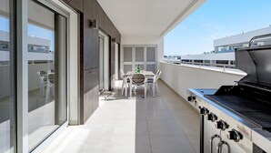 A balcony with a grill, a dining table with chairs, and a view of the city. - Lagos Town Centre Apartment (Lagos)