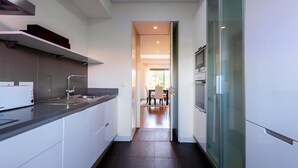 A modern kitchen with white cabinets, a black countertop, and a glass-front refrigerator. - L Orangerie in Vilamoura (Loulé)