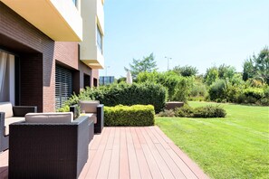 Un'area esterna moderna con un rivestimento in legno, mobili in vimini e un prato curato.