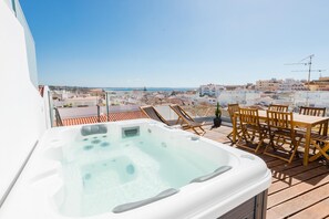 Un jacuzzi en una terraza de madera con vistas a la ciudad y al mar.