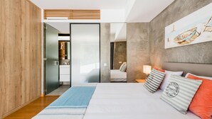 Quarto moderno com cama grande, guarda-roupa de madeira, banheiro e um quadro na parede.