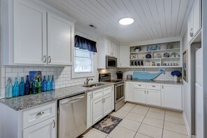 Kitchen features a stainless steel refrigerator, microwave, and oven, along with ample countertop space.