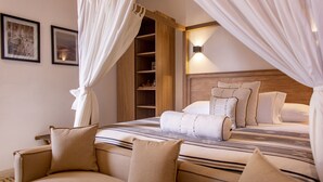 A bedroom with a canopy bed, a wooden headboard, and a nightstand with a lamp. - Sol de Alba Hotel Boutique (Cartagena)