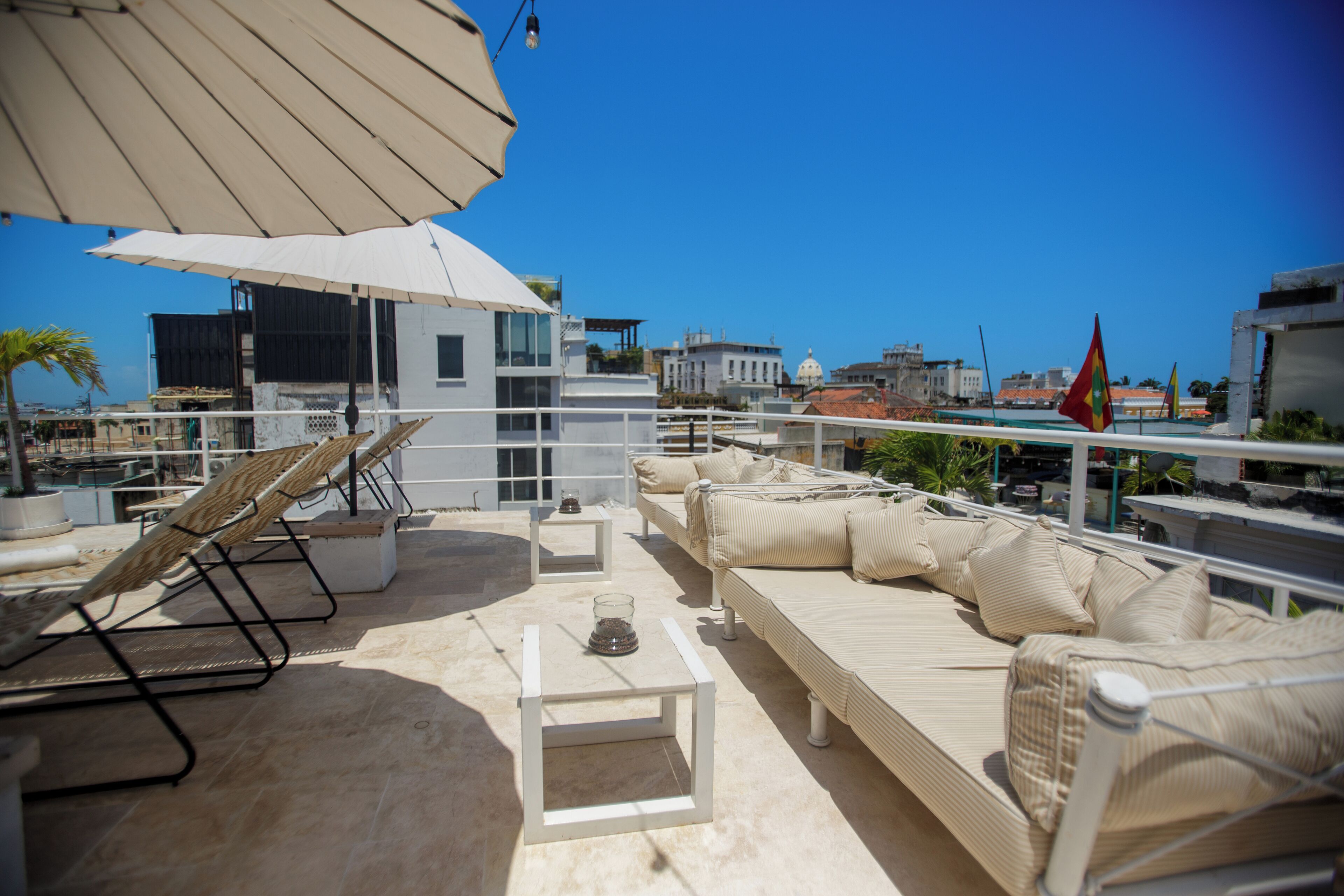 Terraza en la azotea con sillones, tumbonas y una mesa.