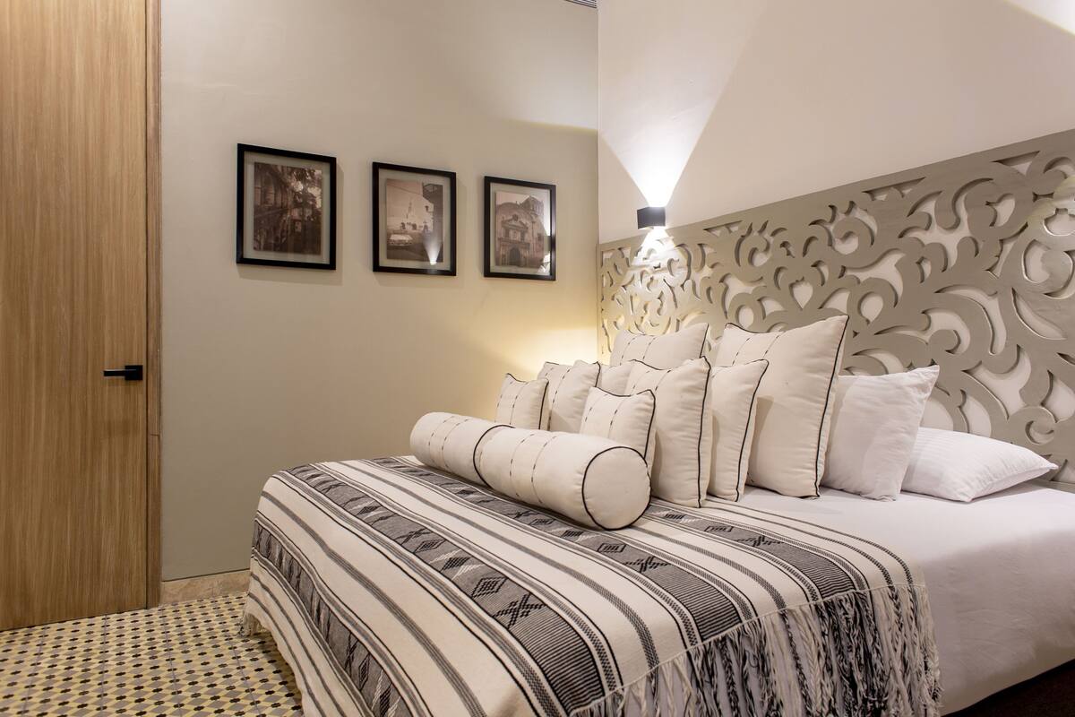 Een slaapkamer met een bed, een kamerbreed tapijt en drie ingelijste foto's aan de muur.