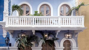 A multi-story building with a white balcony, arched windows, and a wooden door. - Sol de Alba Hotel Boutique (Cartagena)