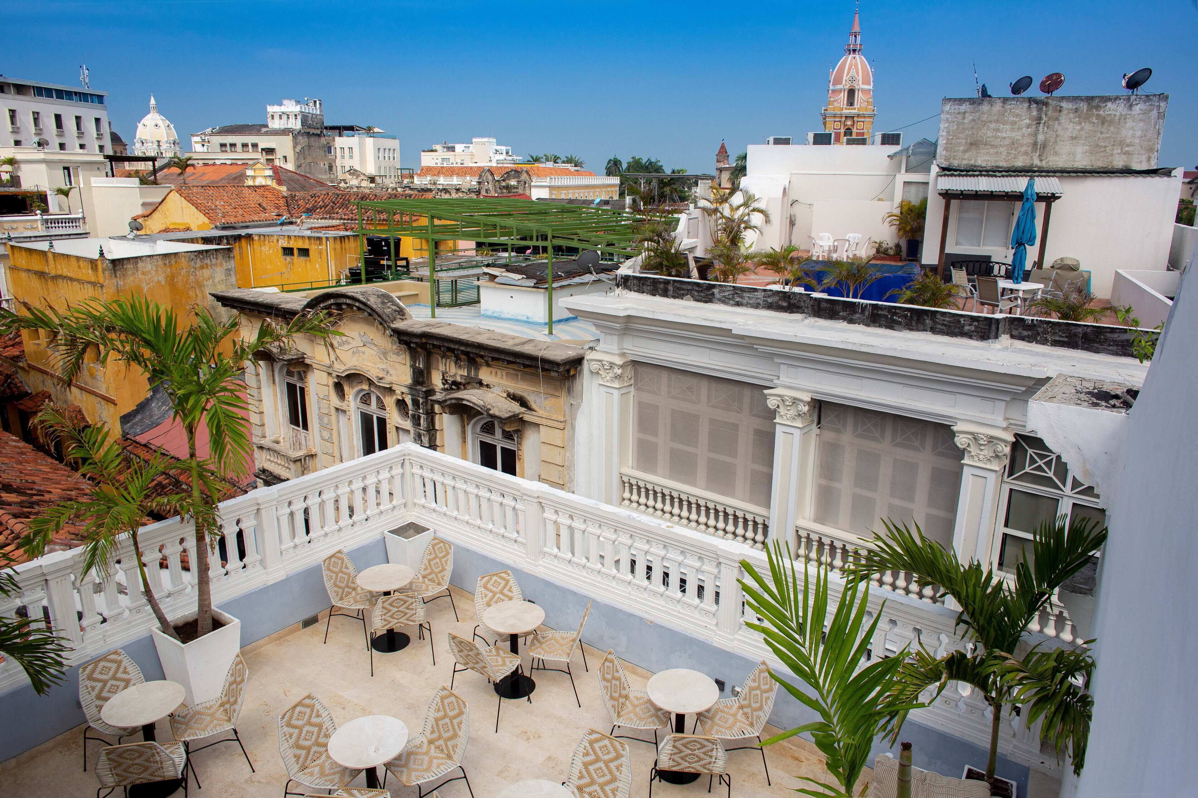 Eine Dachterrasse mit Sitzgelegenheiten im Freien, Blick auf die Stadt und ein markantes Gebäude mit Kuppel im Hintergrund.