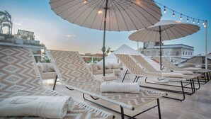 A rooftop lounge area with patterned lounge chairs, large umbrellas, and string lights. - Sol de Alba Hotel Boutique (Cartagena)