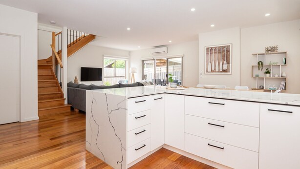 A modern kitchen with white cabinetry, a marble backsplash, and a wooden staircase. - Casa Blue in Dromana (Dromana)
