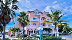 A pink building with balconies, palm trees, and a sign that reads "PULPY." - Convenient Stay in the Heart of Sandyport Olde Towne (Nassau)