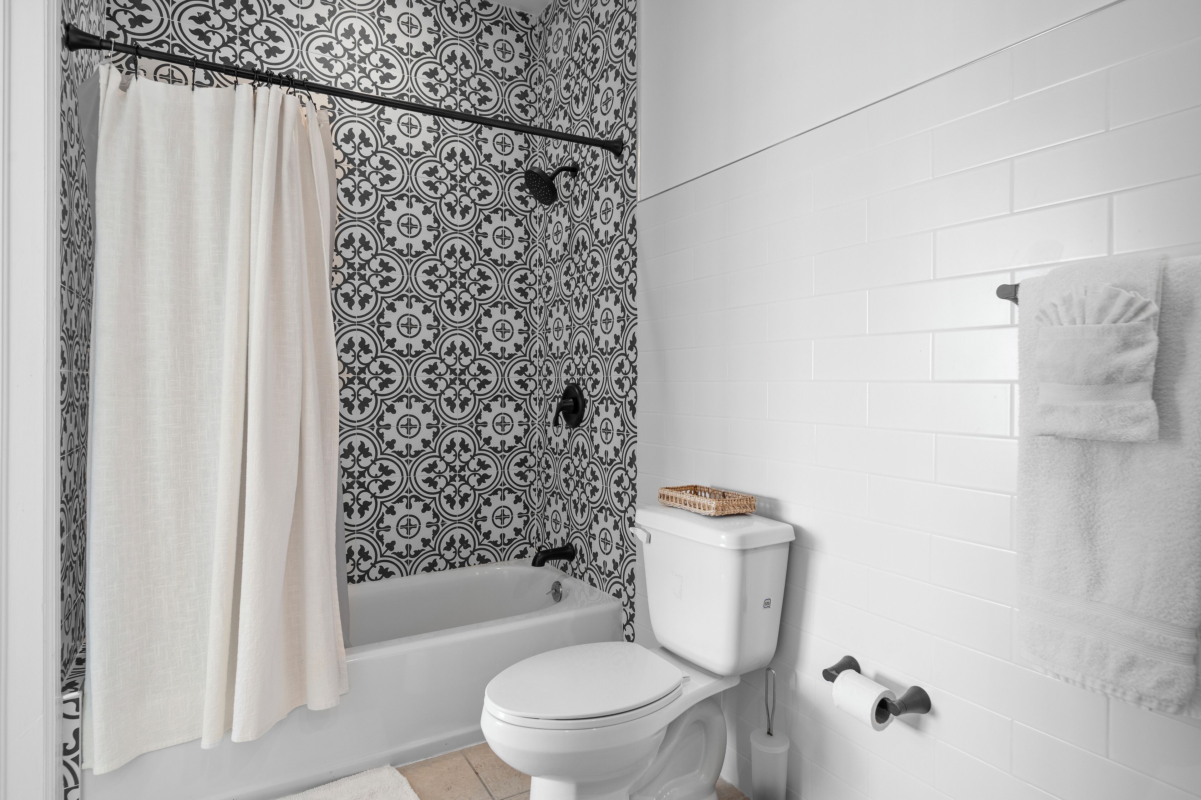 Un baño con cortina de ducha estampada, una bañera, un inodoro y un perchero para toallas.