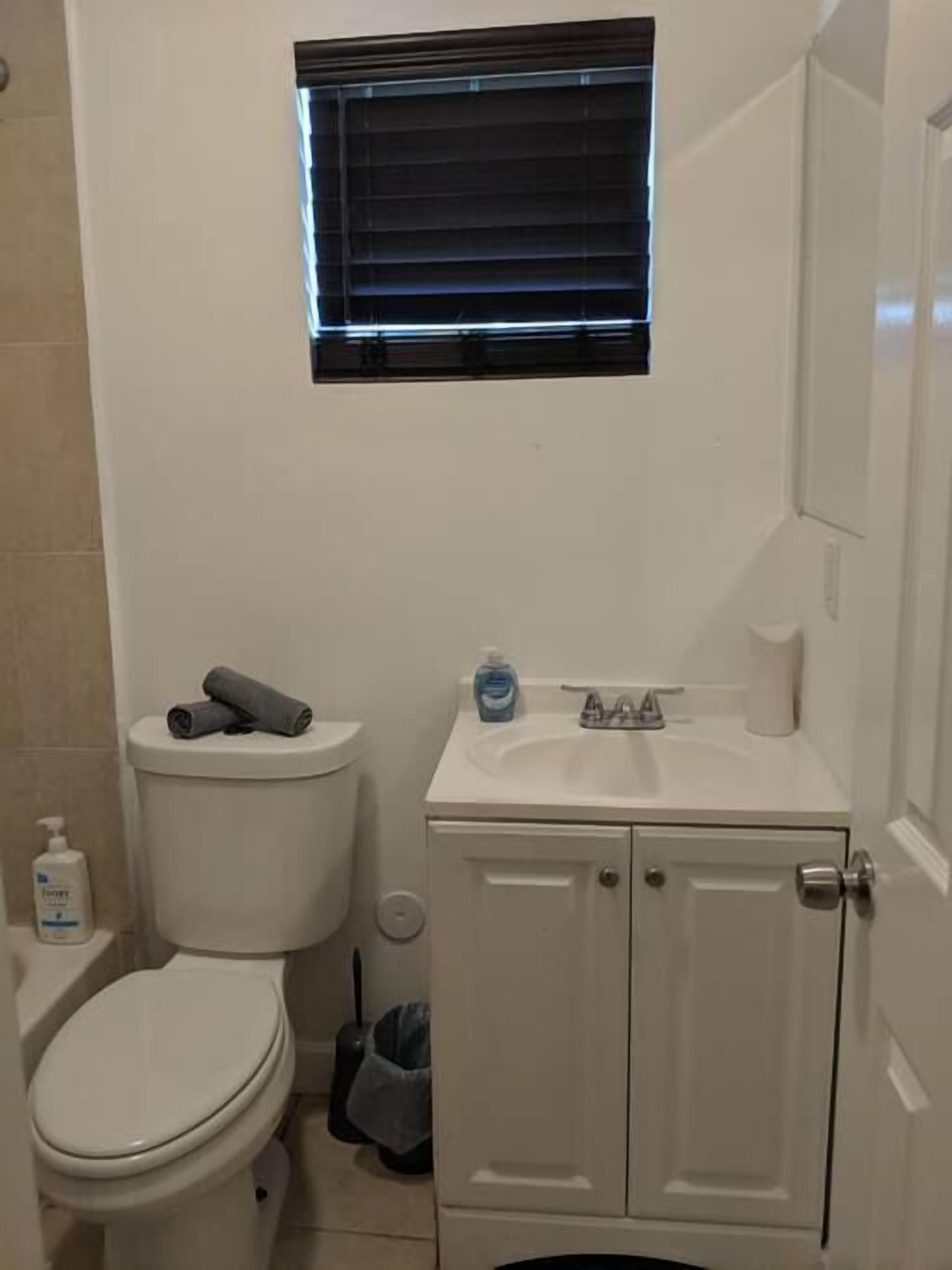 A small bathroom with a toilet, a sink, and a window above the sink.
