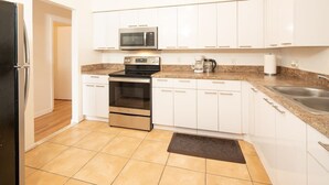A modern kitchen with white cabinets, stainless steel appliances, and a granite countertop. - Modern 5 Bedroom Miami Home, 15 Min. to the Beach! (Miami)