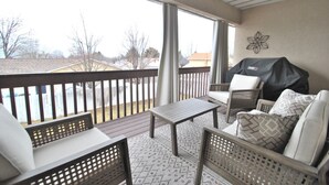 A covered patio with wicker furniture, a table, and a grill.