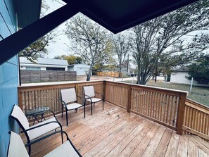 A wooden deck with a railing, two chairs, and a table. - Texas Blue Apple | Pet-Friendly & Near Apple Store (Medina)