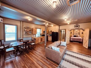 A spacious living area with a dining table, sofa, and kitchen in the background. - Texas Blue Apple | Pet-Friendly & Near Apple Store (Medina)