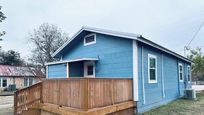 A single-story house with a wooden deck and a blue exterior. - Texas Blue Apple | Pet-Friendly & Near Apple Store (Medina)