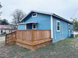 A single-story house with a wooden deck and a blue exterior. - Texas Blue Apple | Pet-Friendly & Near Apple Store (Medina)