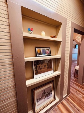 A wall-mounted shelf with framed pictures and decorative items. - Texas Blue Apple | Pet-Friendly & Near Apple Store (Medina)
