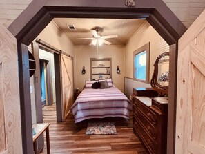 Un dormitorio con cama, cómoda y ventilador de techo.