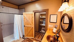 Un bagno con un mobile vanitario in legno, un lavandino, uno specchio e uno spazio doccia.