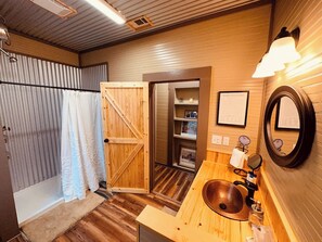 A bathroom with a wooden vanity, a sink, a mirror, and a shower area. - Texas Blue Apple | Pet-Friendly & Near Apple Store (Medina)