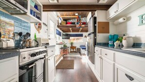 A modern kitchen with white cabinetry, a built-in oven, and a stainless steel refrigerator. - Ashore the Clouds | Glamping Awaits (Woodland Park)