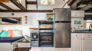 A compact kitchen with white cabinetry, a built-in oven, and a stainless steel refrigerator. - Ashore the Clouds | Glamping Awaits (Woodland Park)