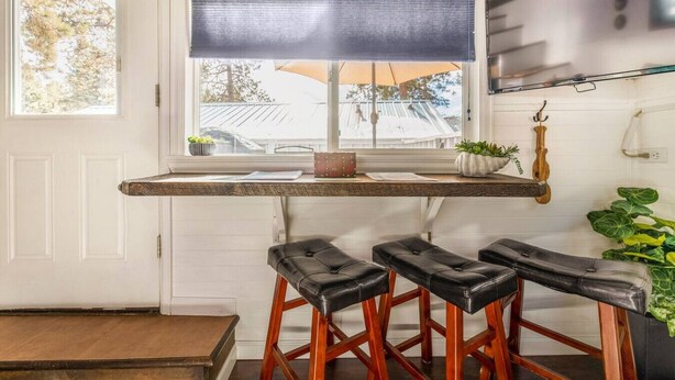 A kitchen with a window, a bar stool area, and a wooden ceiling. - Ashore the Clouds | Glamping Awaits (Woodland Park)